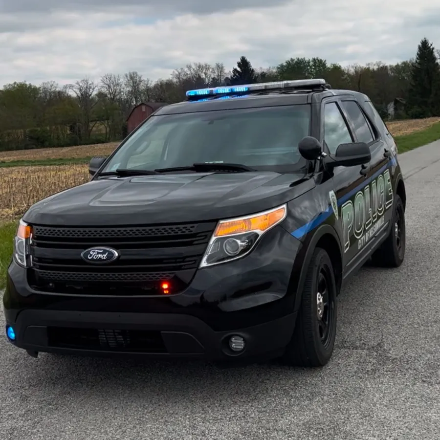 A black police SUV photographed front-on, its full-size roof light bar lit blue and an amber side light showing.