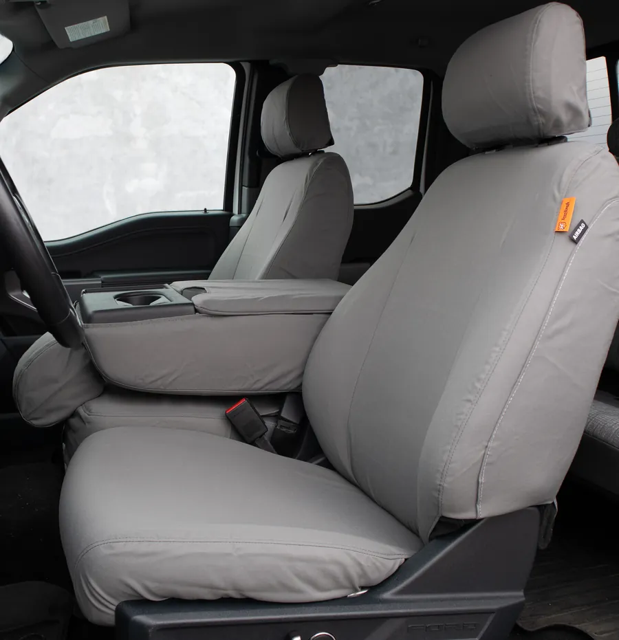 Grey covers on both front seats of a Ford work truck, seen through the driver's door.